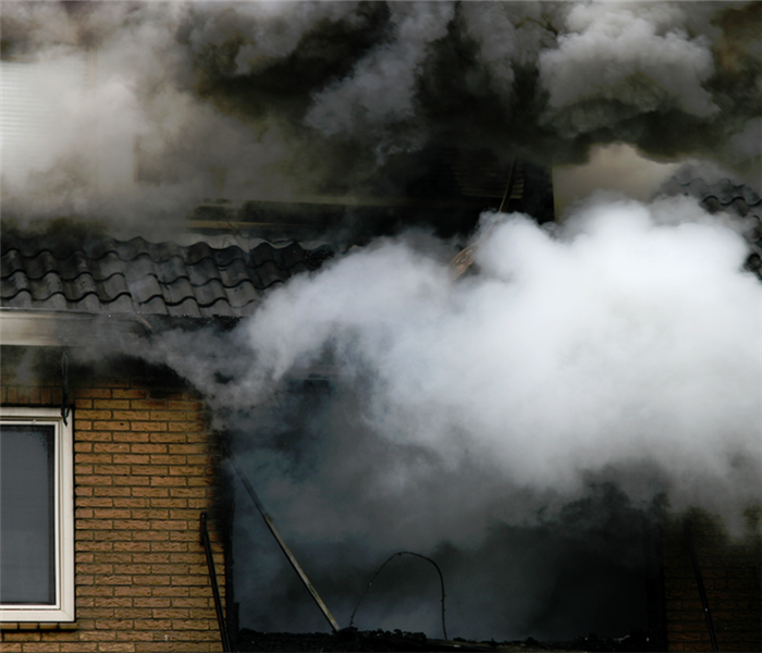 smoke billowing from the windows of a house that is on fire
