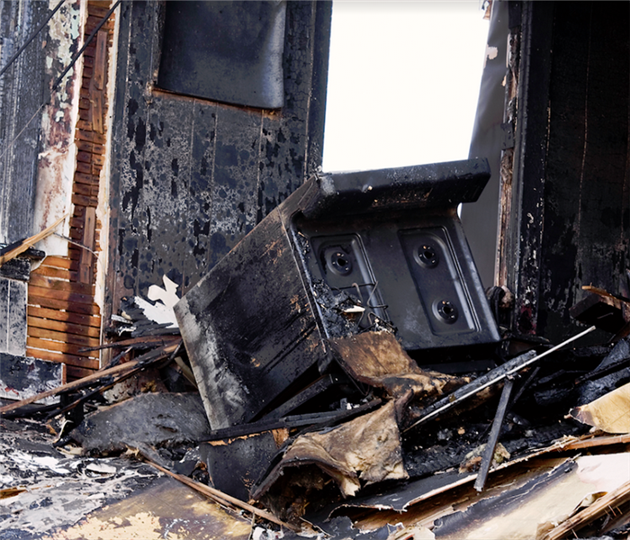 a soot covered oven in a fire damaged room
